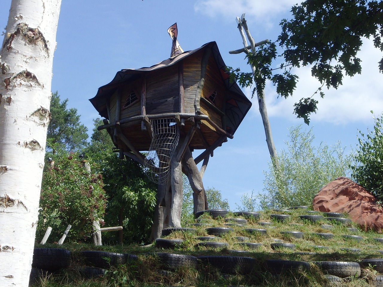 Boomhut met hangmat tussen groene bomen.